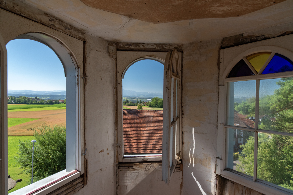 Das Bild zeigt ein kleines Turmzimmer mit Fenstern die eine schöne Weitsicht über die umliegenden Felder bietet.