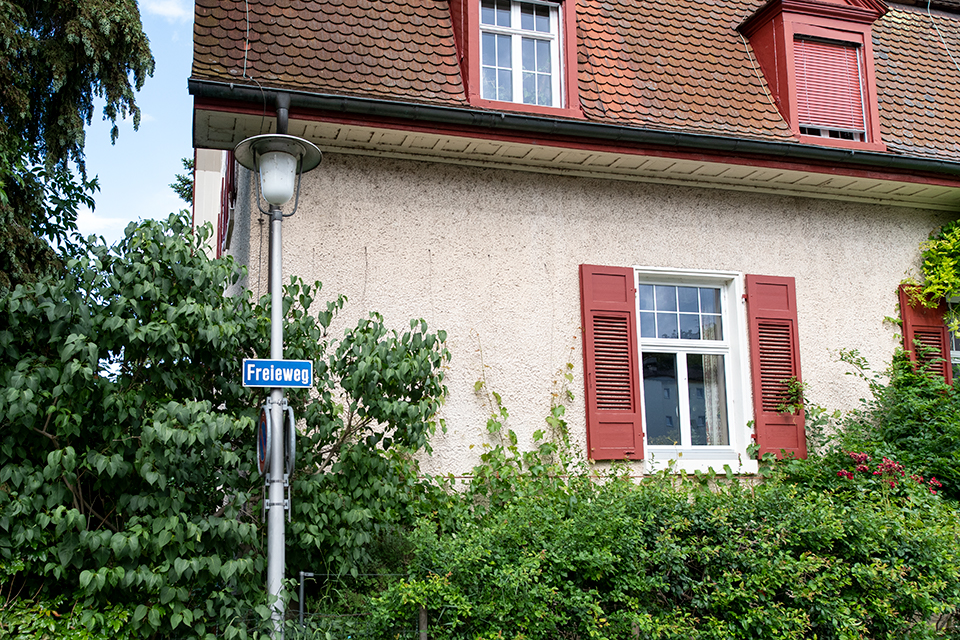 Das Bild zeigt das Strassenschild, Freieweg, und im Hintergrund ein Einfamilienhaus.
