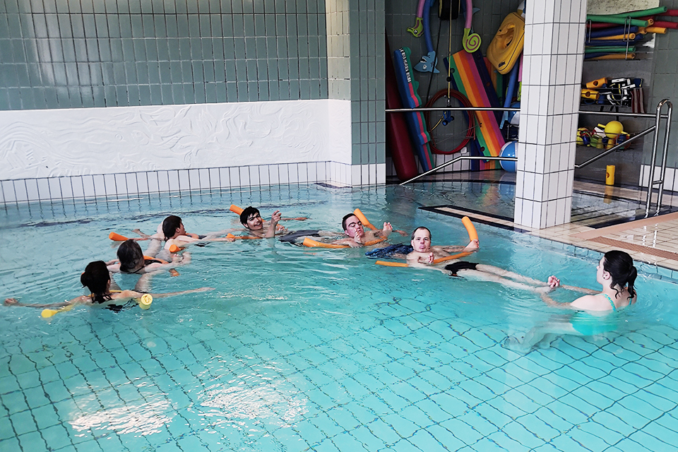 Das Bild zeigt eine Gruppe von Menschen beim Rückenschwimmen.