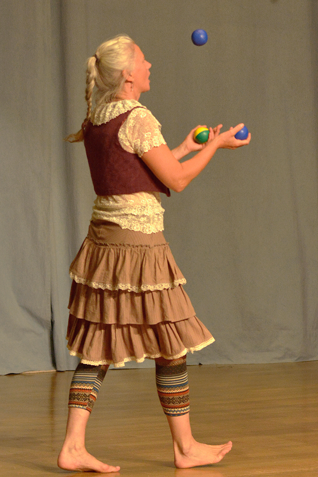 Das Bild zeigt eine Frau beim Jonglieren mit drei Bällen.