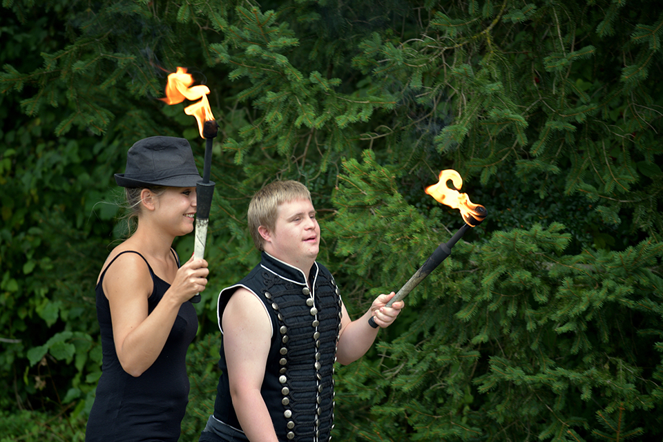 Das Bild zeigt eine Frau und einen Mann mit einer brennenden Fackel in der Hand.