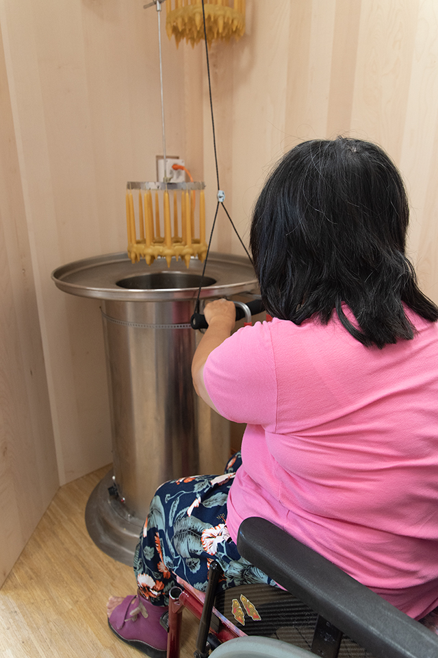 Das Bild zeigt eine Frau im Rollstuhl an einer Kerzentauchstation.