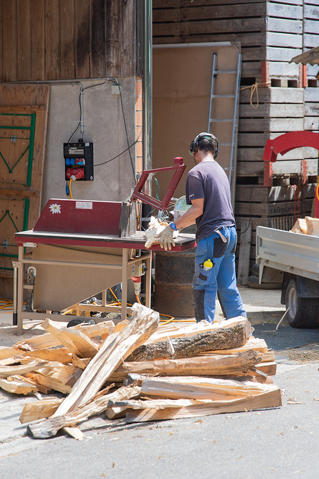 Das Bild zeigt einen Mann der Brennholz zusägt.