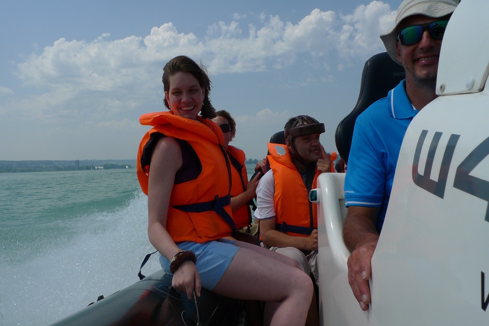 Das Bild zeigt mehrere Menschen mit Rettungsweste die auf einem Boot sitzen.