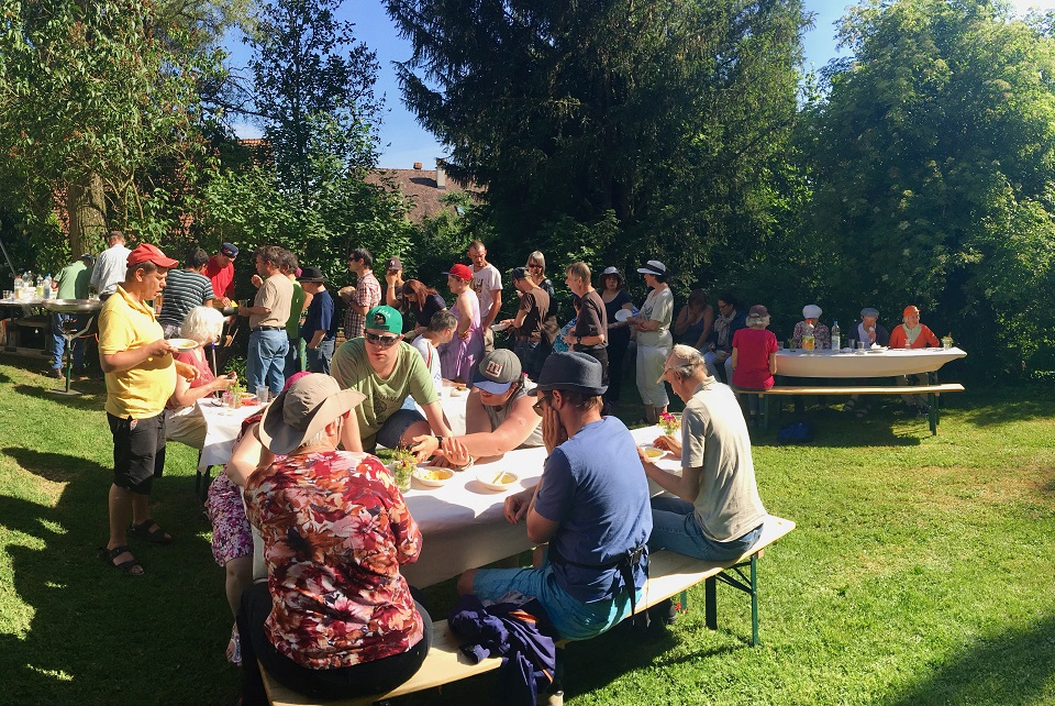 Das Bild zeigt Menschen an Biertischen die ein Sommerfest feiern.
