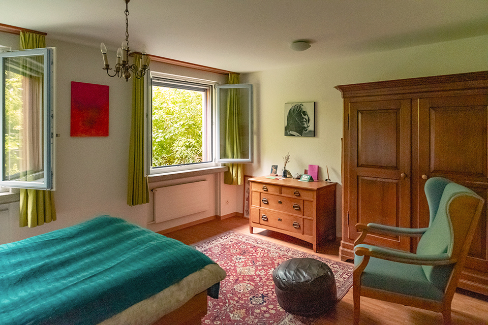 Das Bild zeigt ein Schlafzimmer mit Bett, Sessel, Kommode und Kleiderschrank. Das Zimmer ist in der Farbe Grün gehalten.