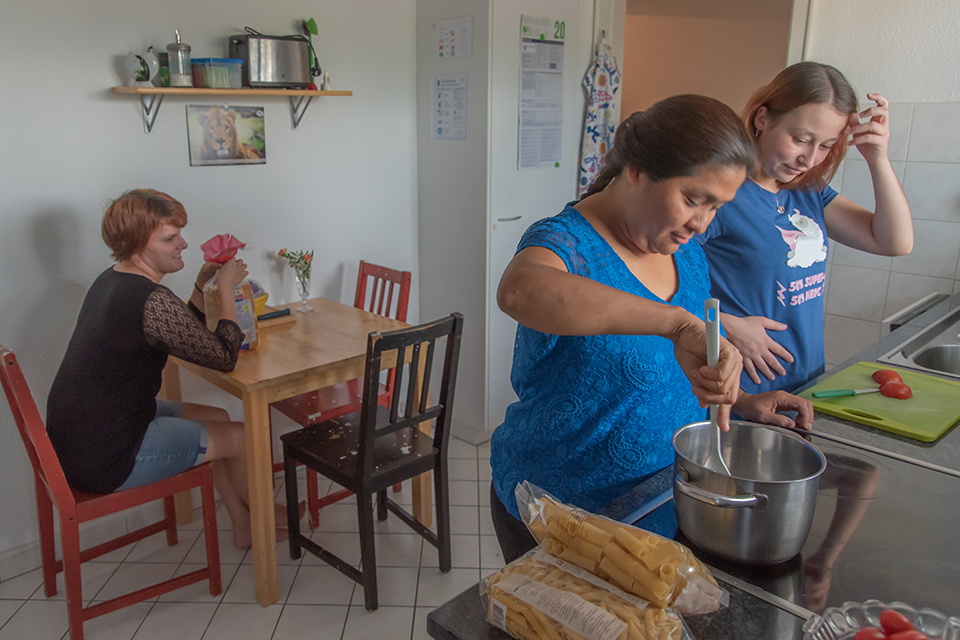 Das Bild zeigt drei Frauen beim gemeinsamen Kochen.