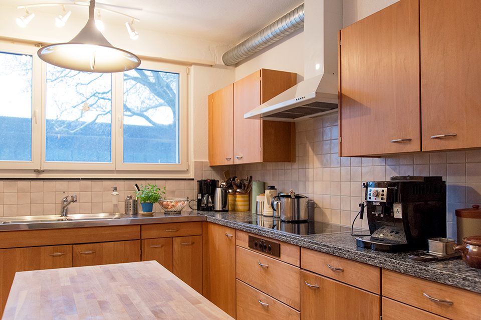 Das Bild zeigt eine Küche mit einer Holzfront und einem Holztisch in der Mitte des Raumes.