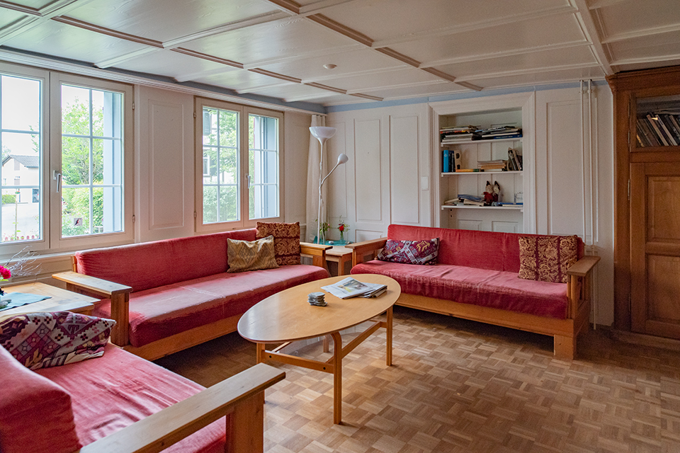 Das Bild zeigt ein Wohnzimmer mit roten Sofas und einem Wohnzimmertisch aus hellem Holz.