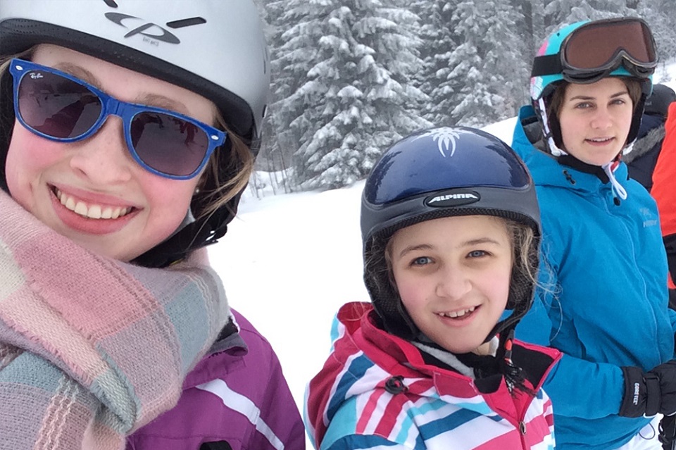 Das Bild zeigt drei Schülerinnen mit Skihelmen bekleidet.
