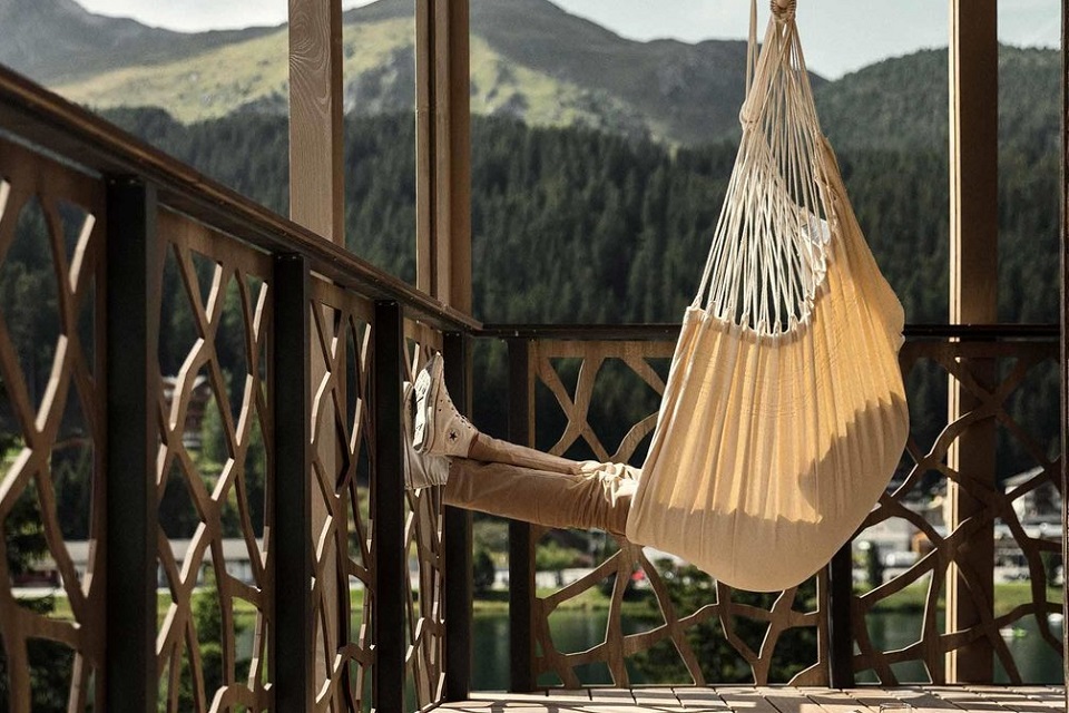 Das Bild zeigt eine Hängematte auf einem Holzbalkon mit Sicht in die Berge.