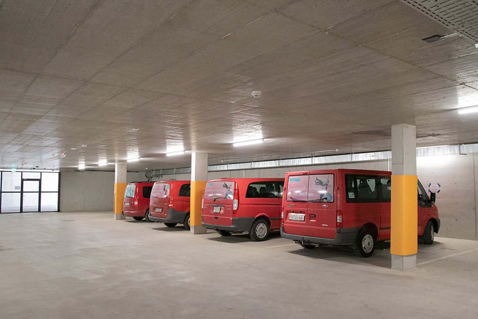 Das Bild zeigt vier rote Kleinbusse in einer Tiefgarage geparkt.