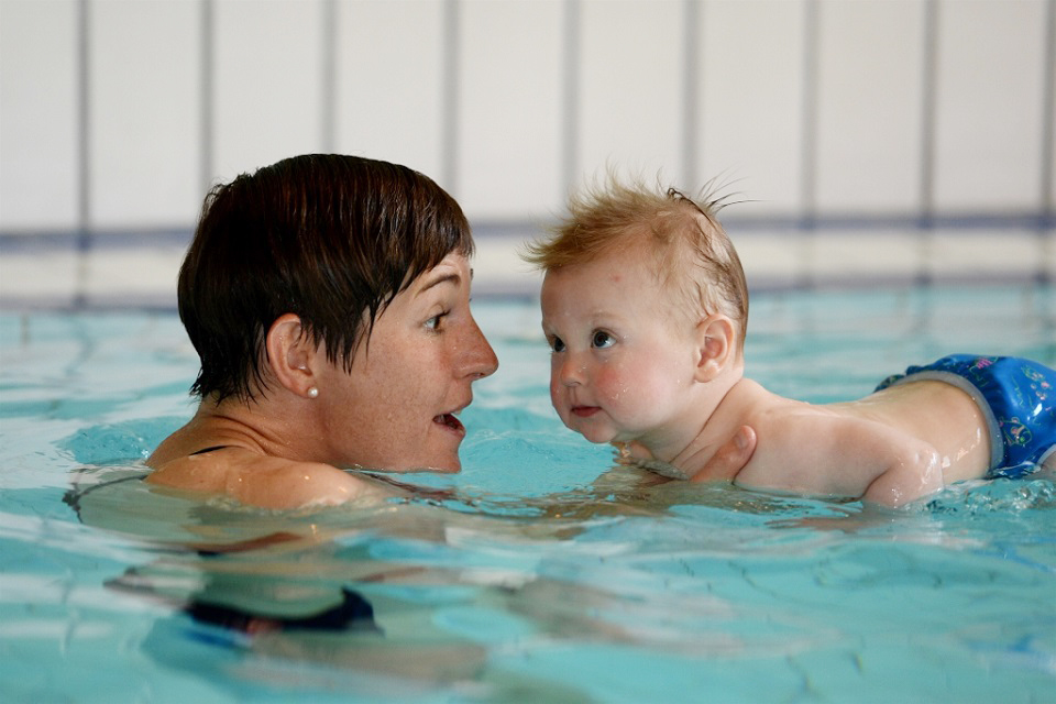 Das Bild zeigt eine Mutter mit ihrem Kind beim Schwimmen.