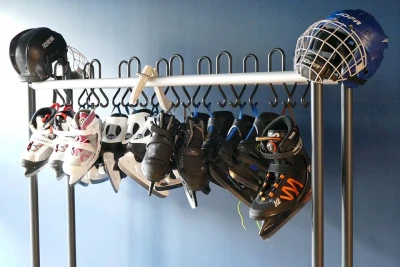 Zu sehen ist eine Garderobe, an der Schlittschuhe sowie zwei Eishockeyhelme hängen.