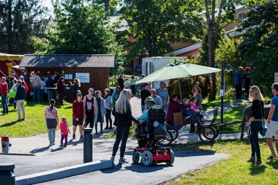 Man sieht einen Ausschnitt des Herbstfestes. Zu sehen sind viele Besucher und Besucherinnen, darunter Kinder und ein Mensch mit Rollstuhl.