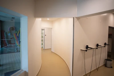 Man blickt auf dem Flur im Schwimmbad, an der Wand sind Föhne befestigt.