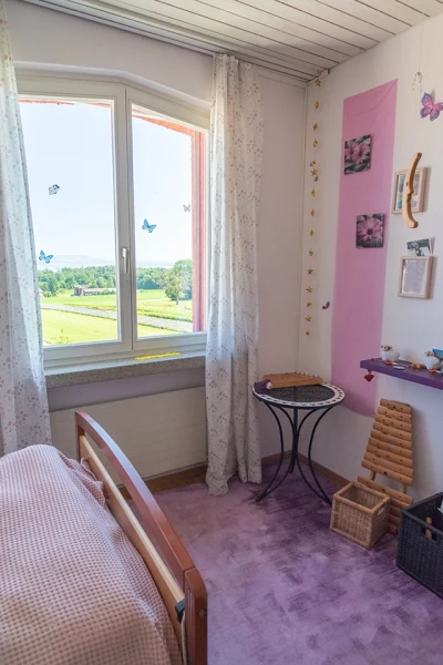 Einen Blick in ein Zimmer der Wohngruppe «Michael» mit Blick nach draussen. Das Fenster ist mit Schmetterlingen dekoriert.