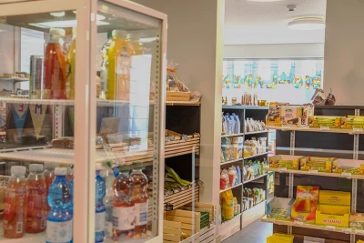 Man sieht verschiedene Produktregale im Bio-Laden. im Vordergrund steht ein kleiner verglaster Kühlschrank mit Erfrischungsgetränken.